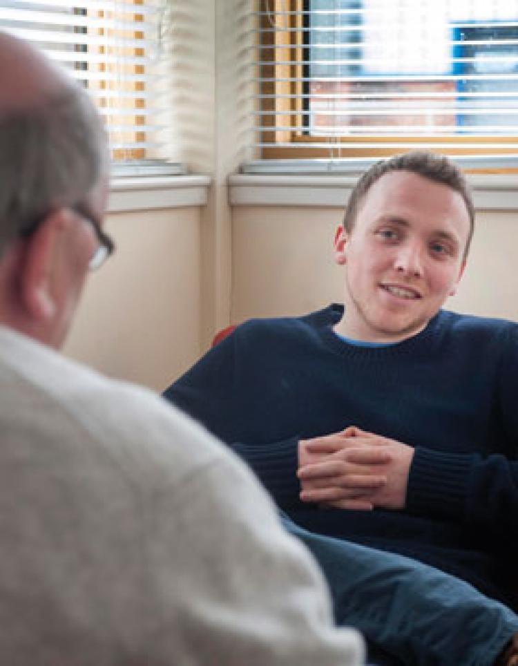 2 men casually seated, talking