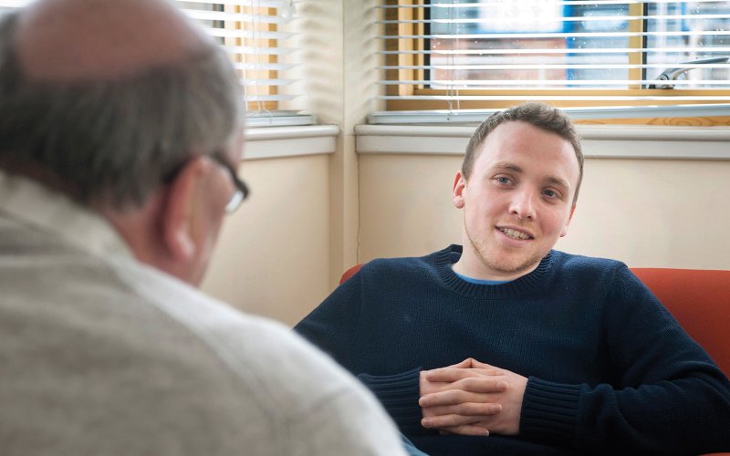 2 men casually seated, talking